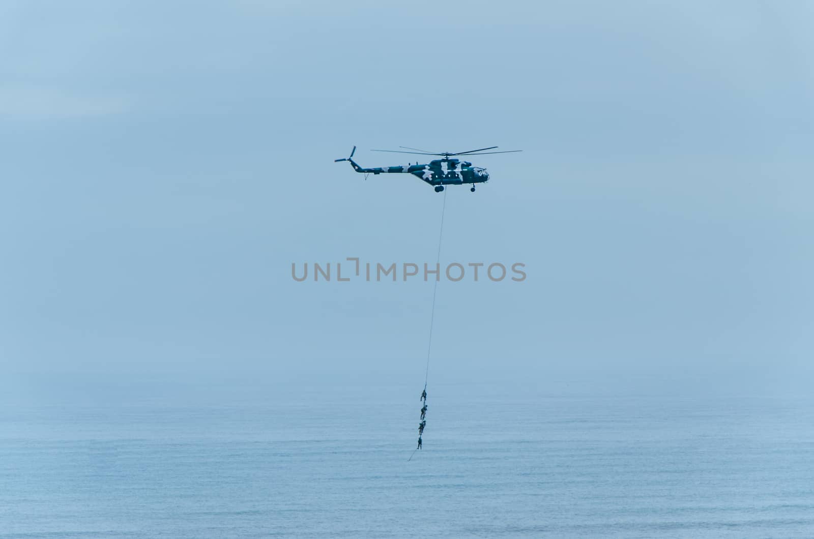 Four men hanging on a rope in a helicopter, doing tests, training