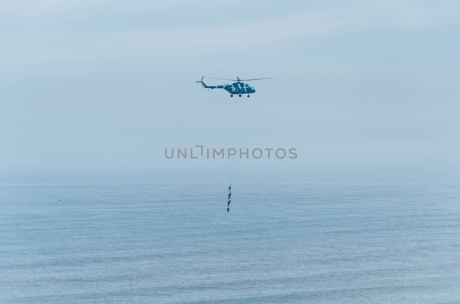 Four men hanging on a rope in a helicopter, doing tests, training