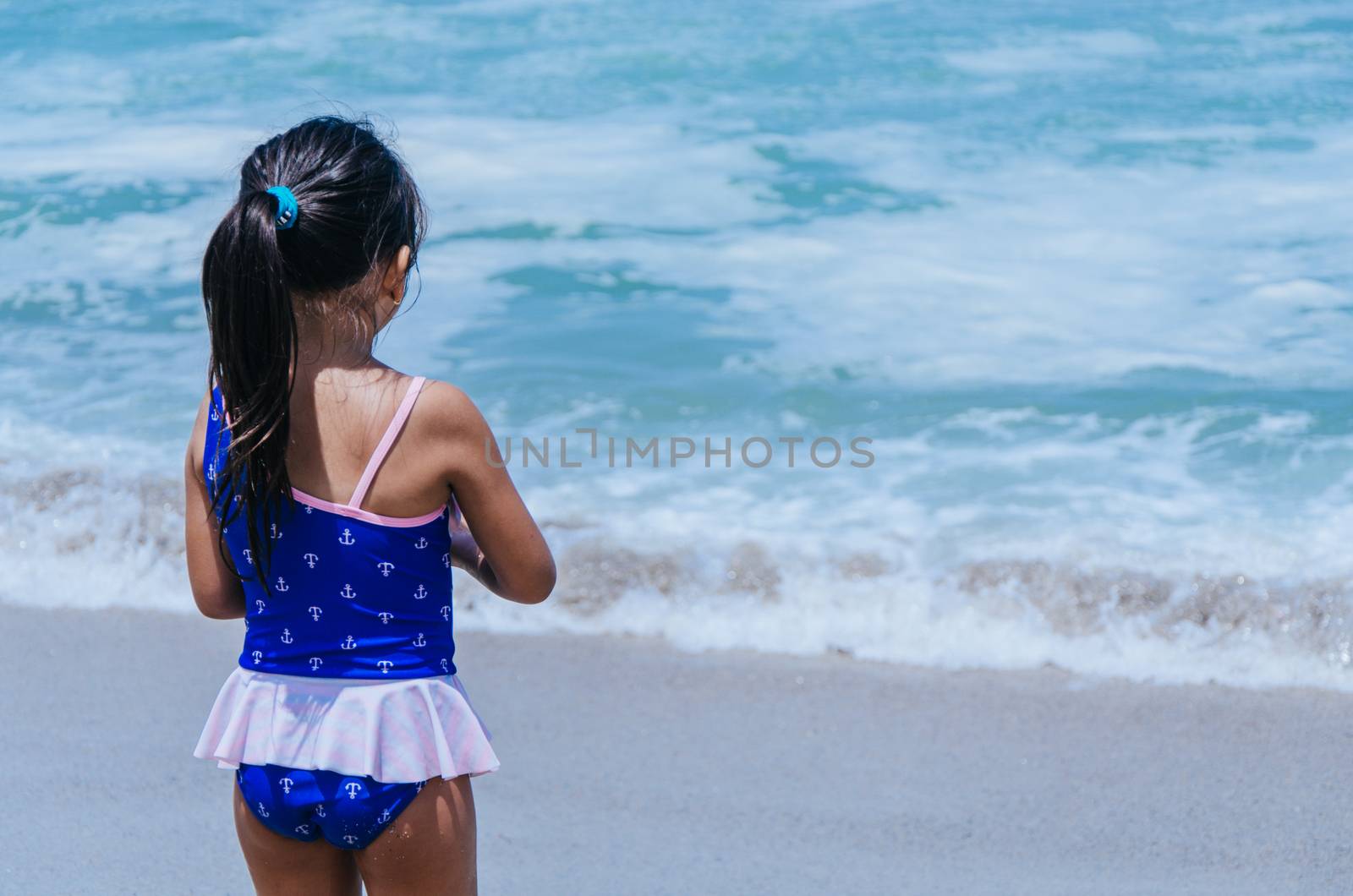 Hands of little girl play with sand on beach