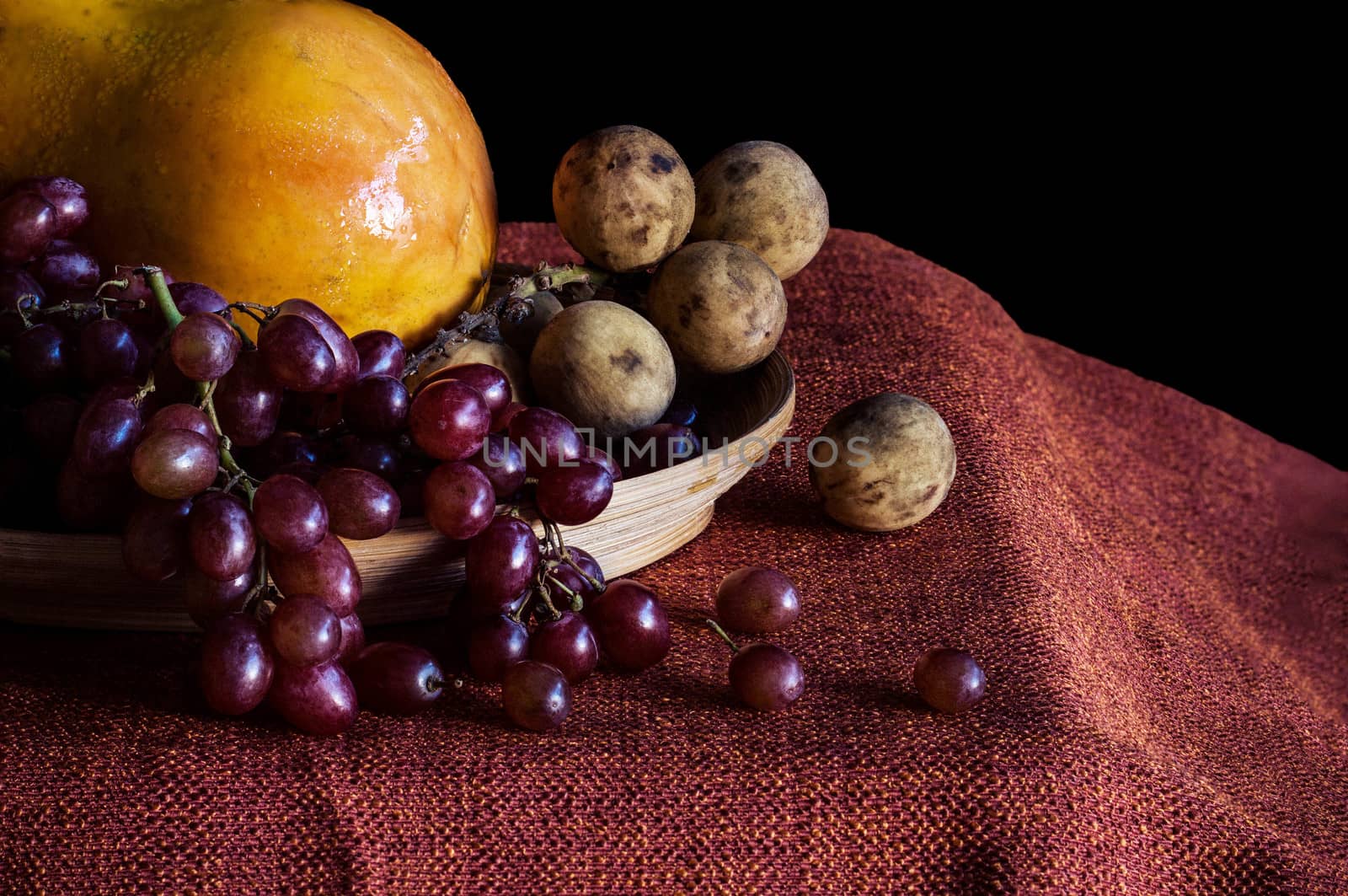 Grapes and papaya on the table with a black background.