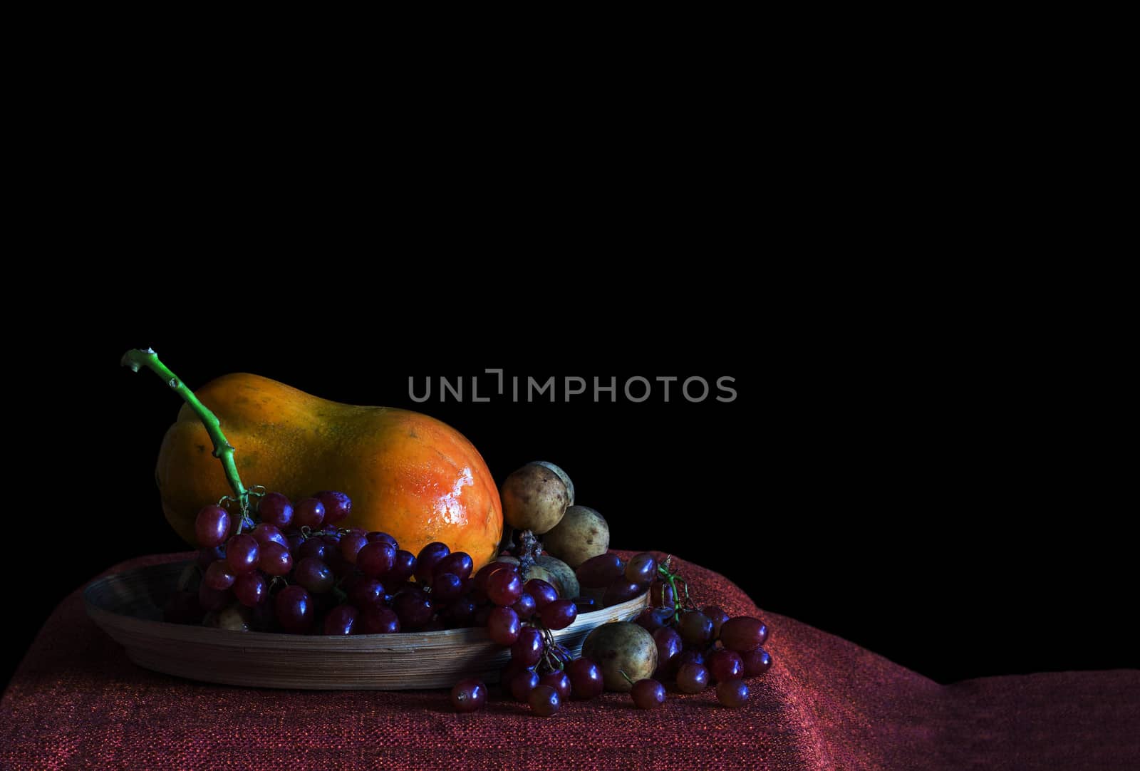 Grapes and papaya on a tray with a black background.