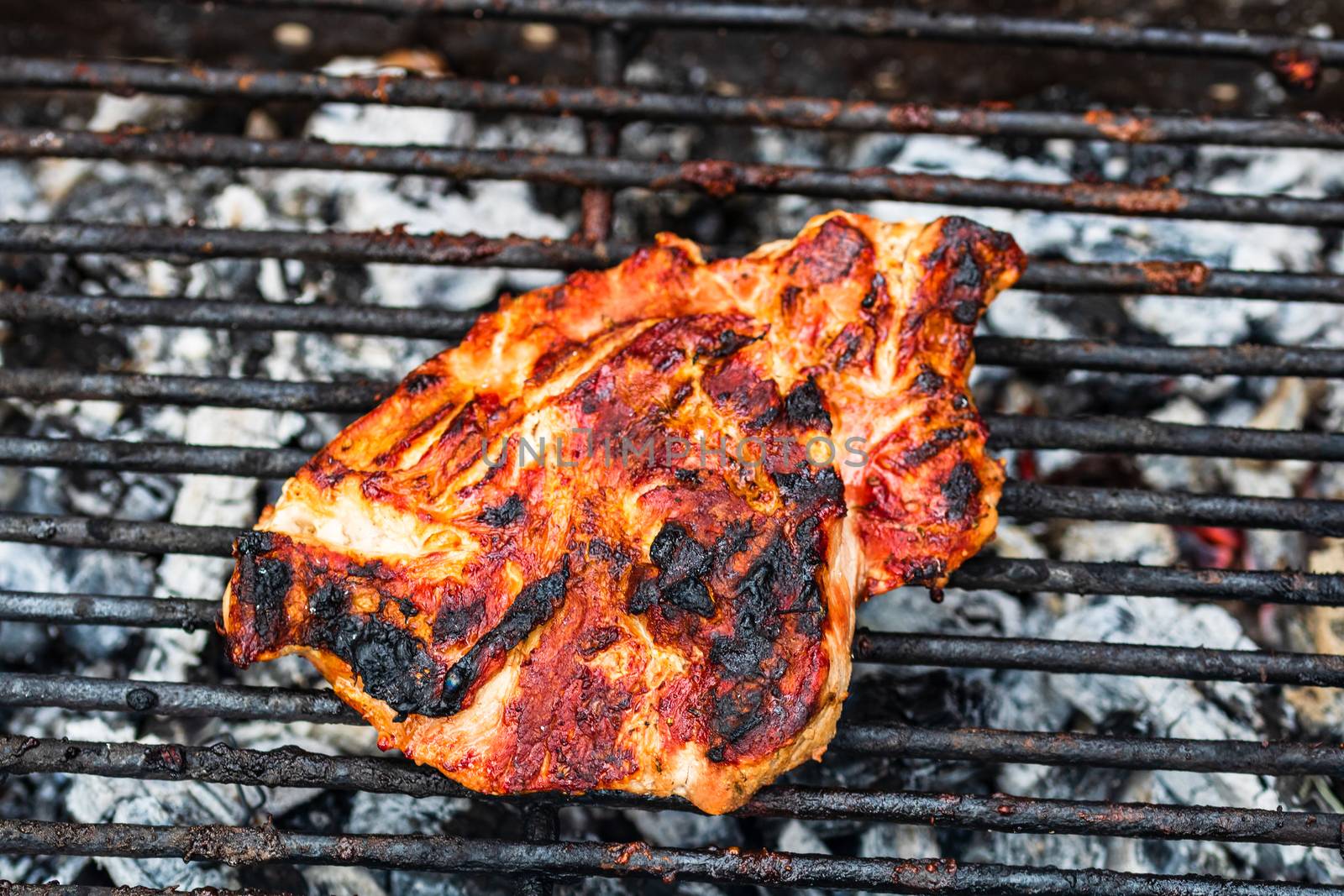 Close up of pork steak grilled on a charcoal barbeque isolated.