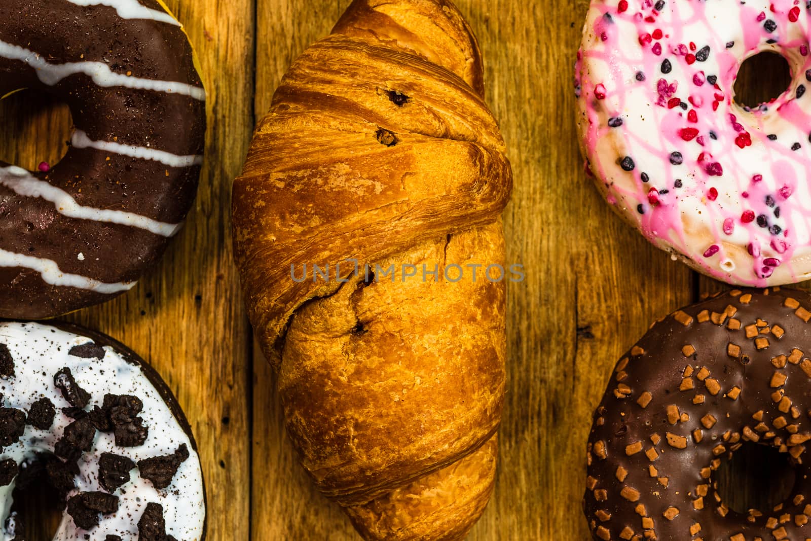 Colorful donuts on wooden table. Sweet icing sugar food with gla by vladispas