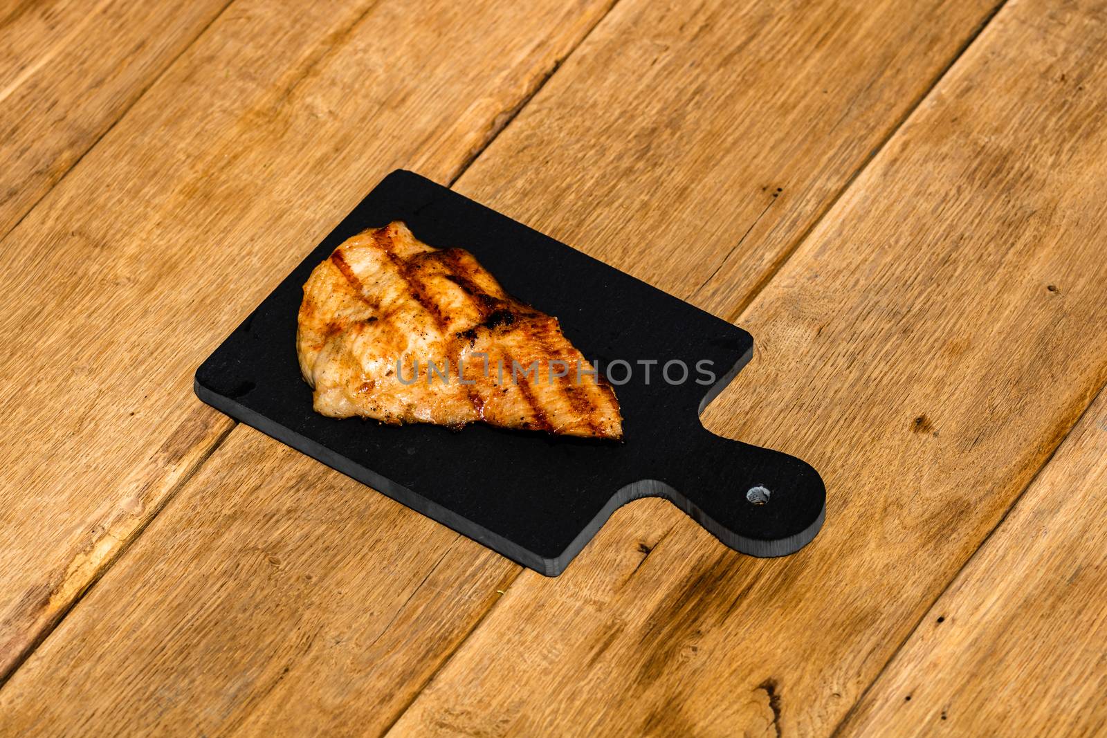 Close up of grilled steak on small black chopping board isolated by vladispas