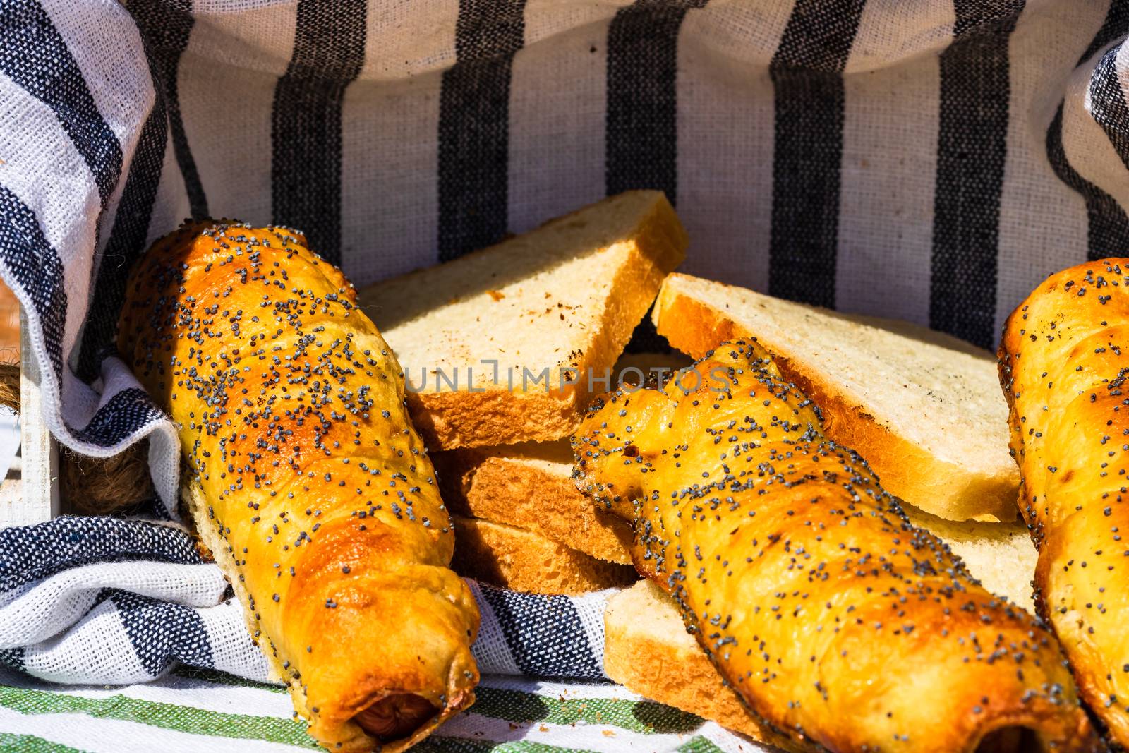 Sausages baked in dough sprinkled with salt and poppy seeds in a by vladispas