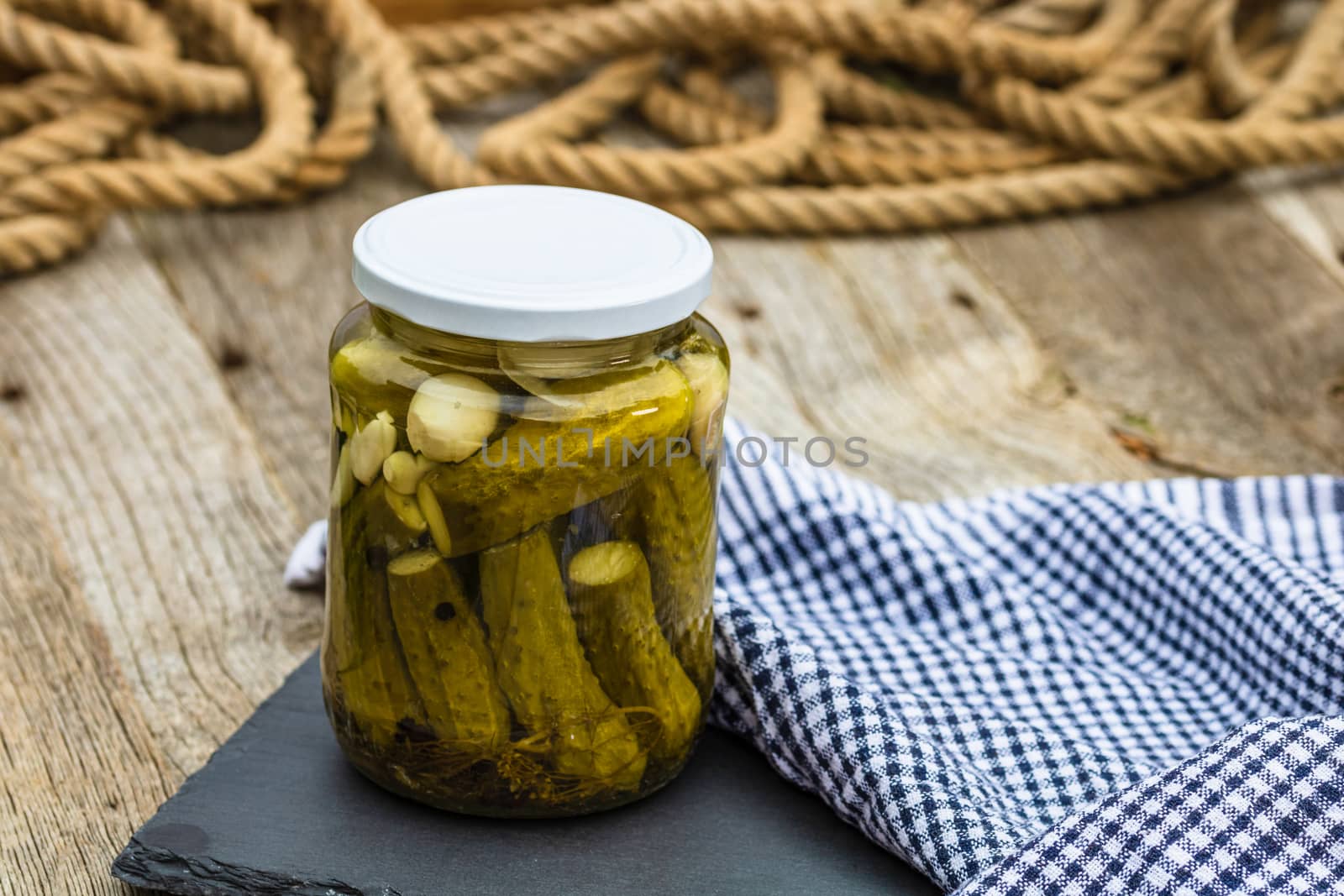 Close up of glass jar with pickles isolated. Preserved food concept, canned vegetables isolated in a rustic composition.