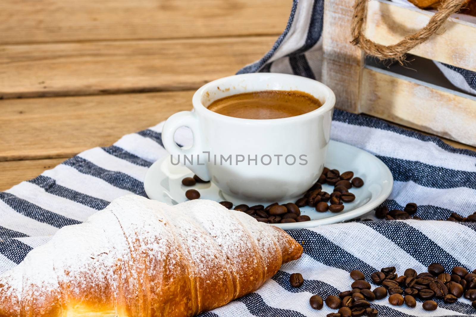 Puff pastry, coffee cup and buttered French croissant on wooden crate. Food and breakfast concept. Detail of coffee desserts and fresh pastries