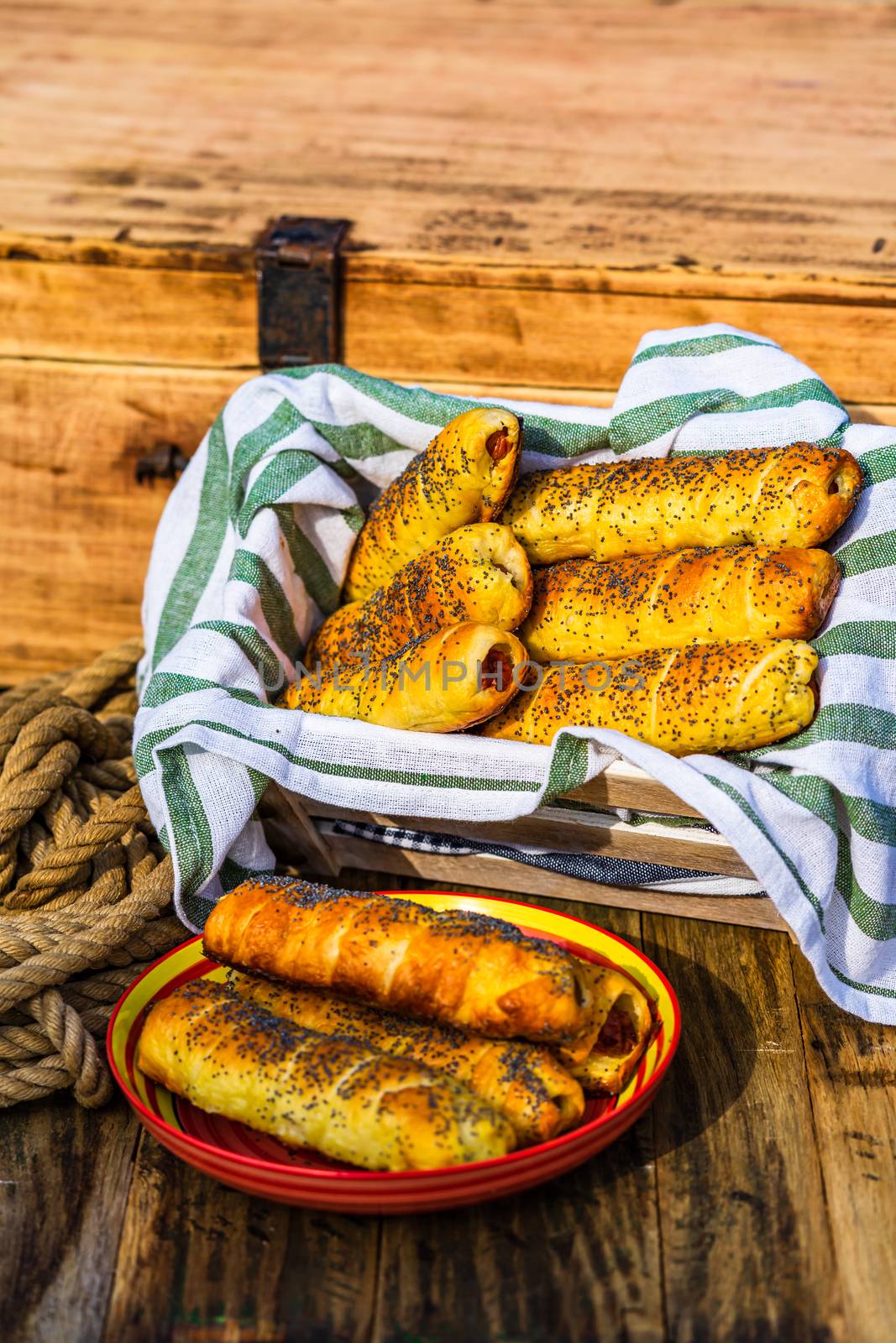 Sausages baked in dough sprinkled with salt and poppy seeds in a by vladispas
