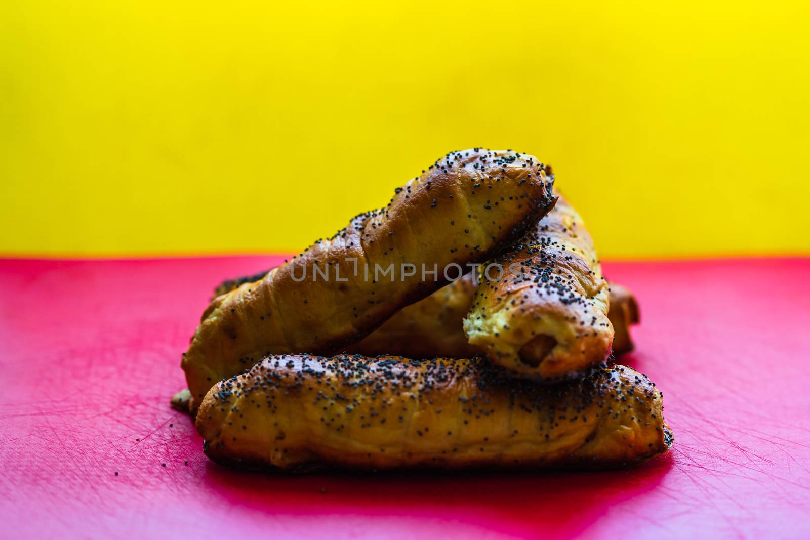 Close up of sausages baked in dough sprinkled with salt and poppy seeds. Sausages rolls, delicious homemade pastries isolated.