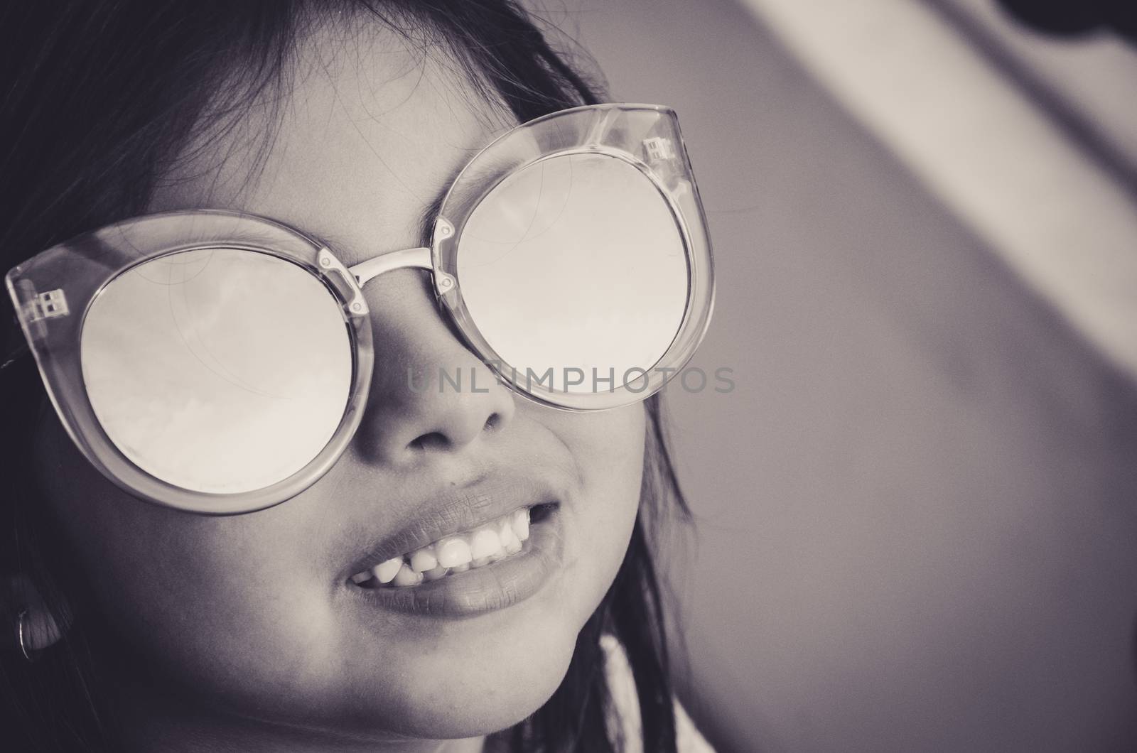 Cute little girl smiling with adult sun glasses