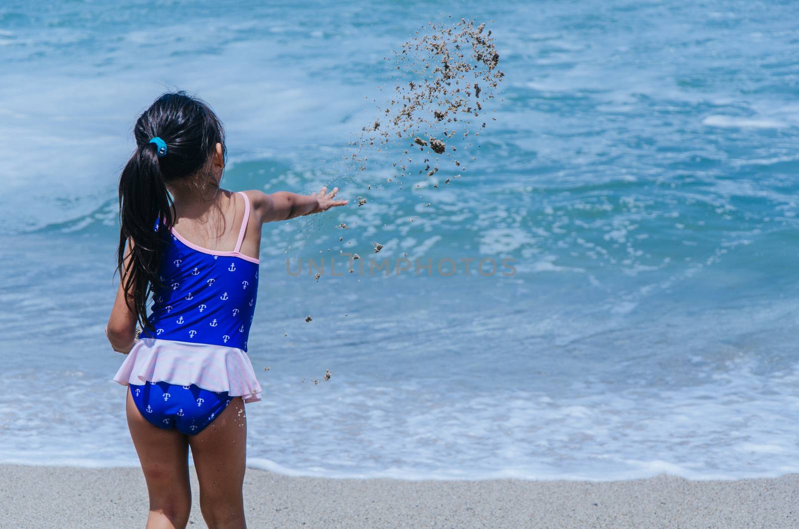 Hands of little girl play with sand on beach