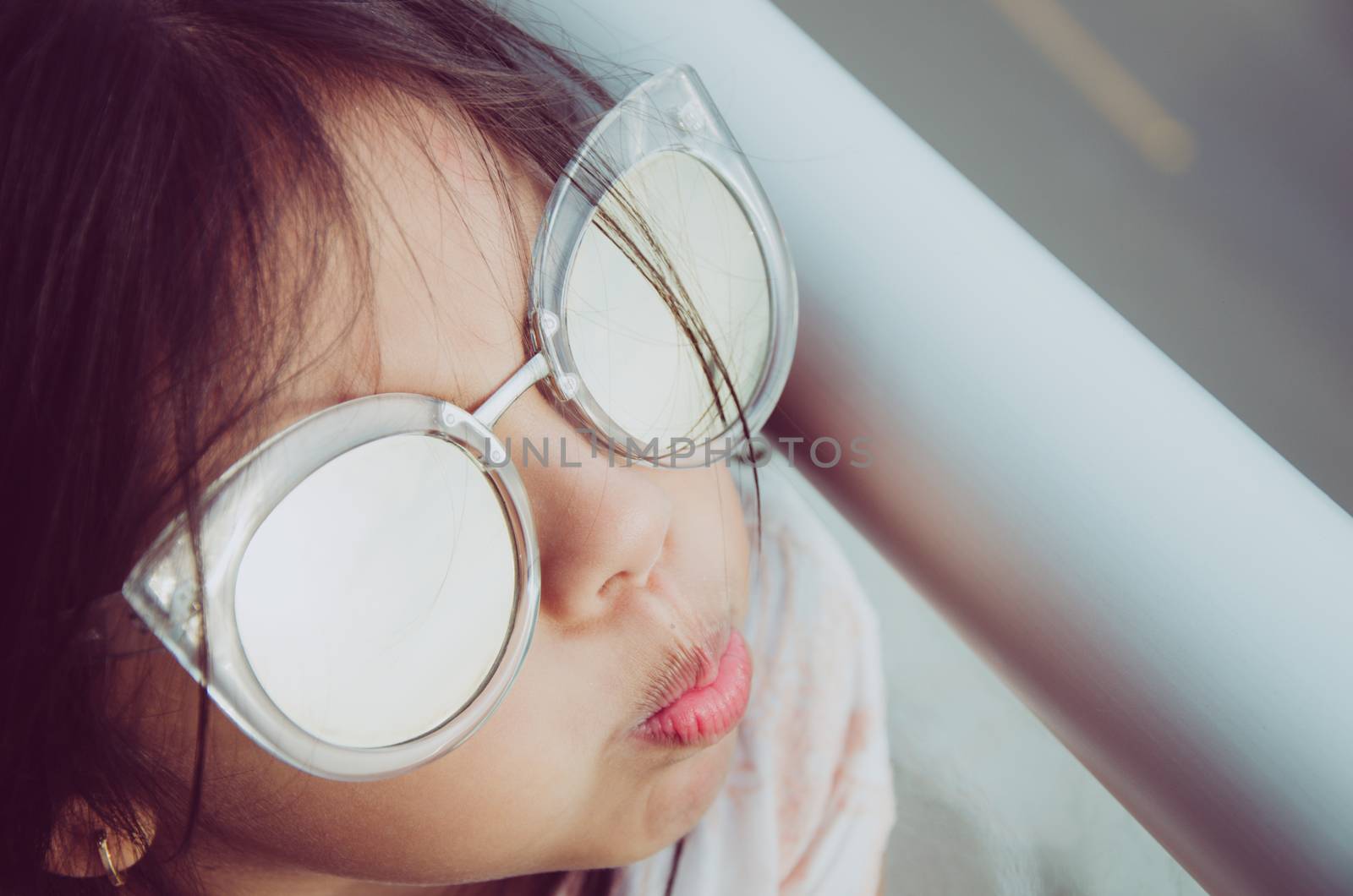 Cute little girl smiling with adult sun glasses