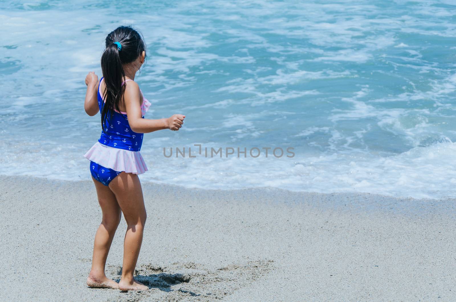 Hands of little girl play with sand on beach