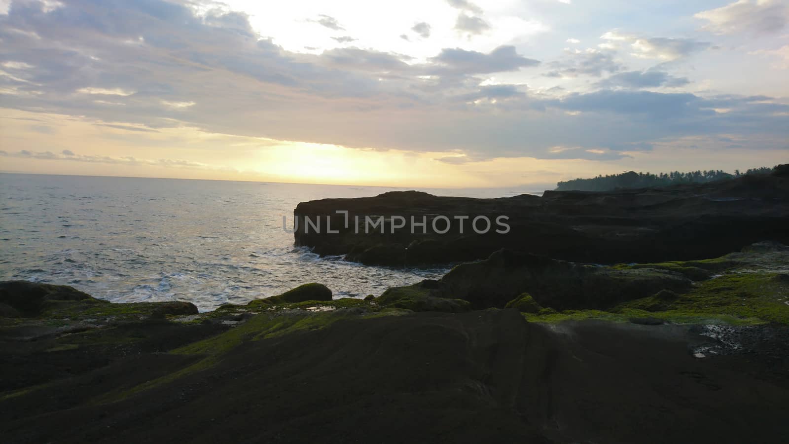 Sunset over the ocean. View of rocks, large waves by Passcal