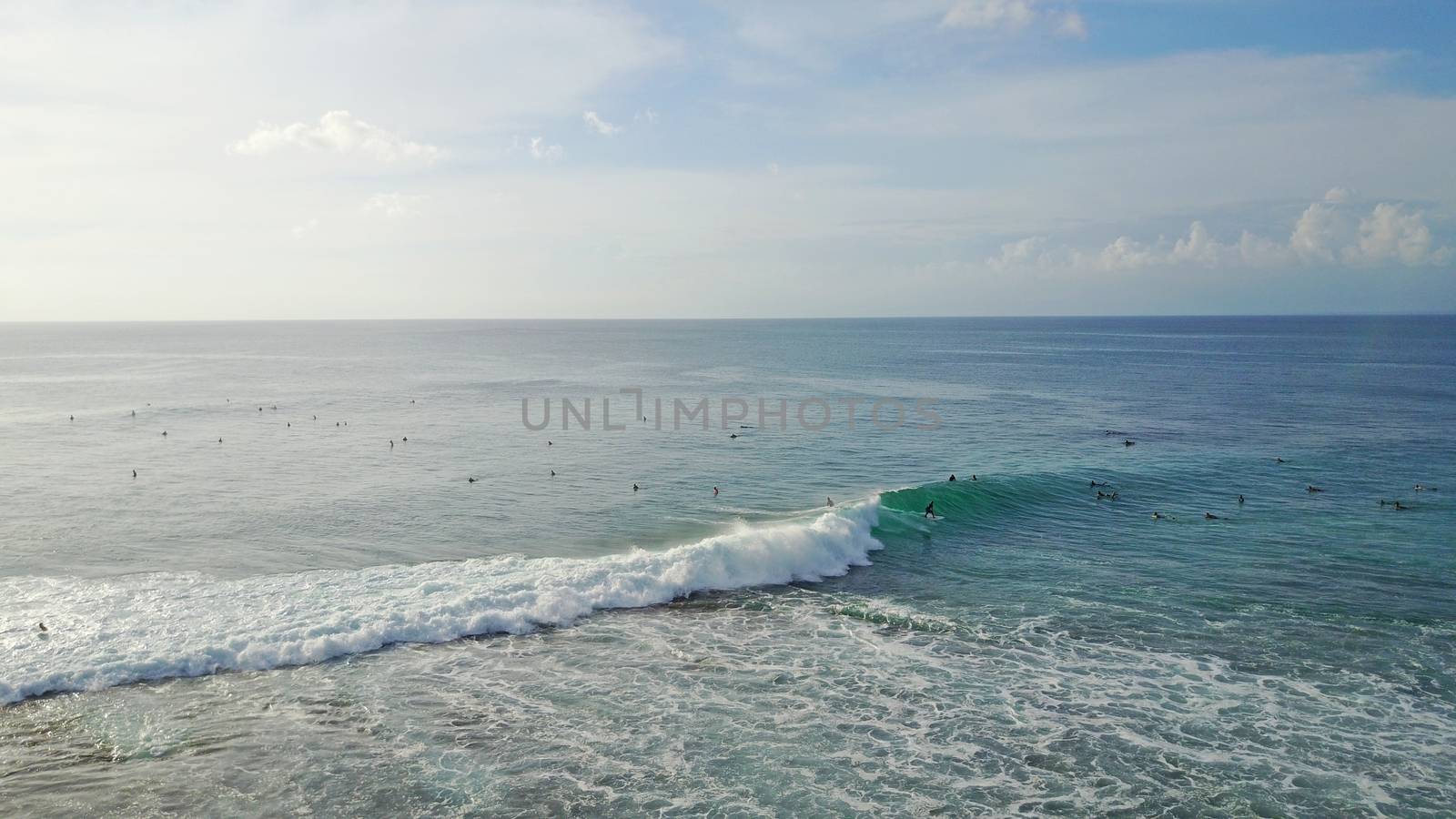 Surfers catch waves on the beach of Bali, Uluwatu by Passcal