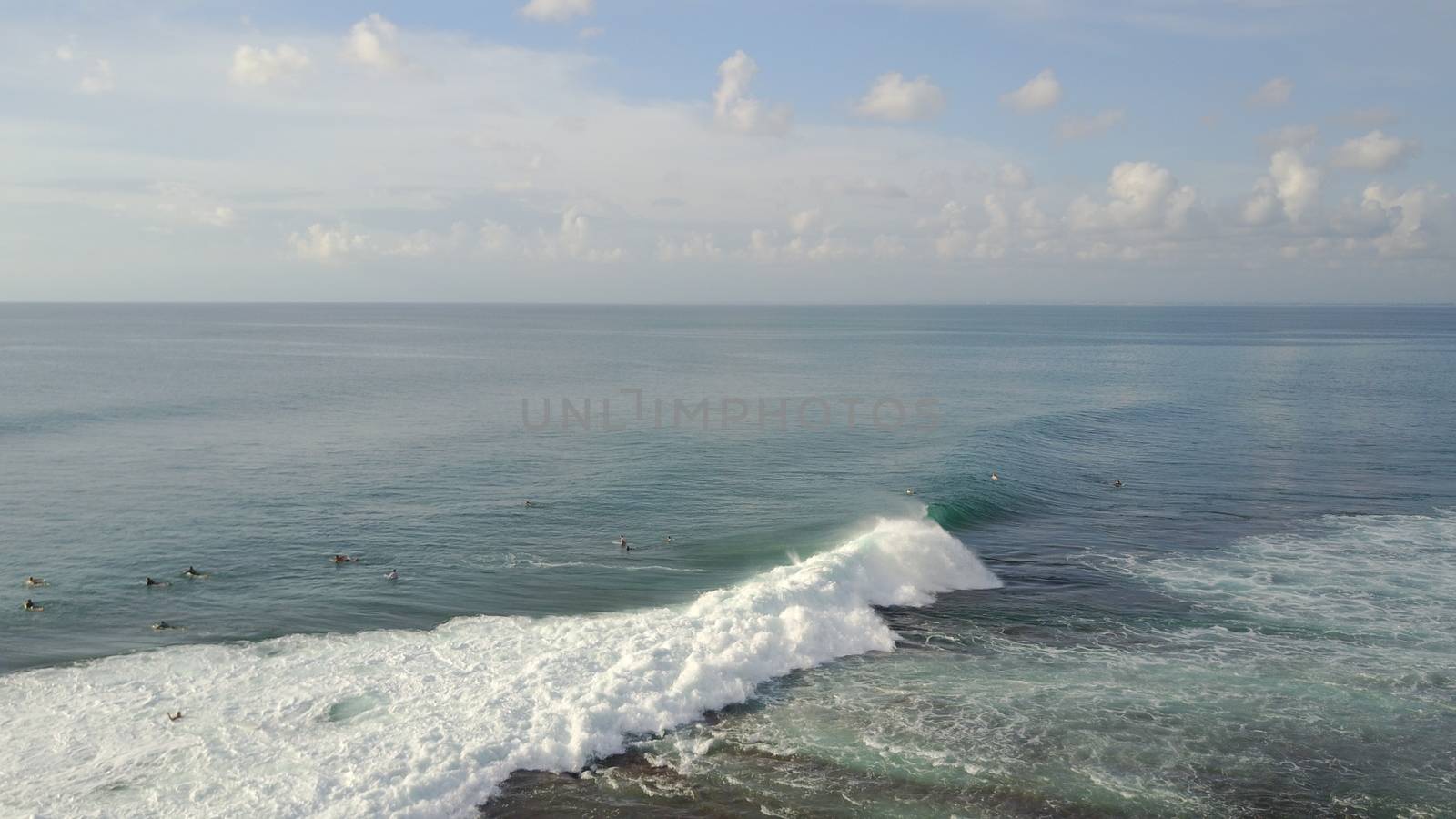 Surfers catch waves on the beach of Bali, Uluwatu by Passcal