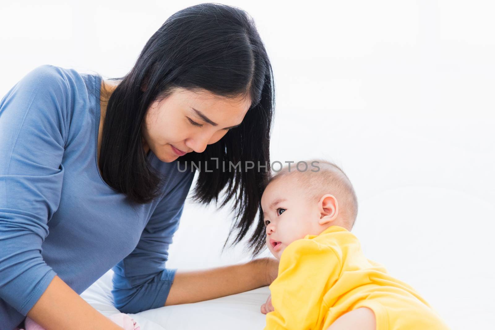 Portrait of beautiful young Asian mother holding and feeding infant newborn baby from milk bottle in a white bed, The child drinking milk from mom, Healthcare and medical