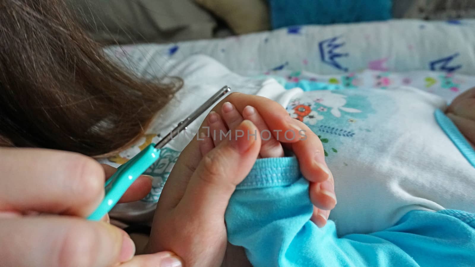 A newborn child's nails are cut with scissors. by Passcal