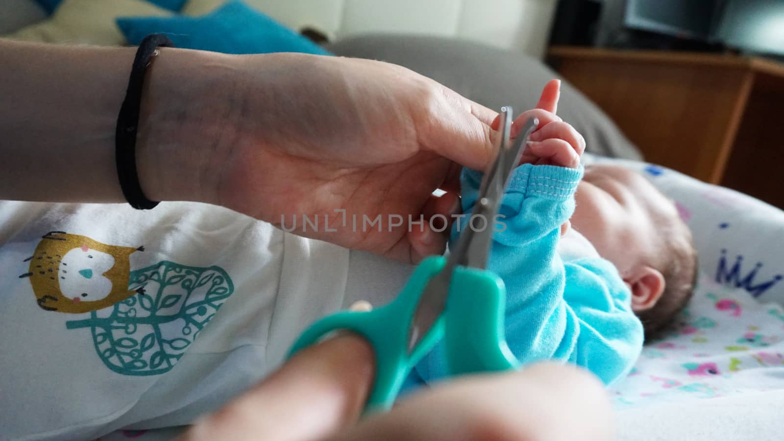 A newborn child's nails are cut with scissors. by Passcal