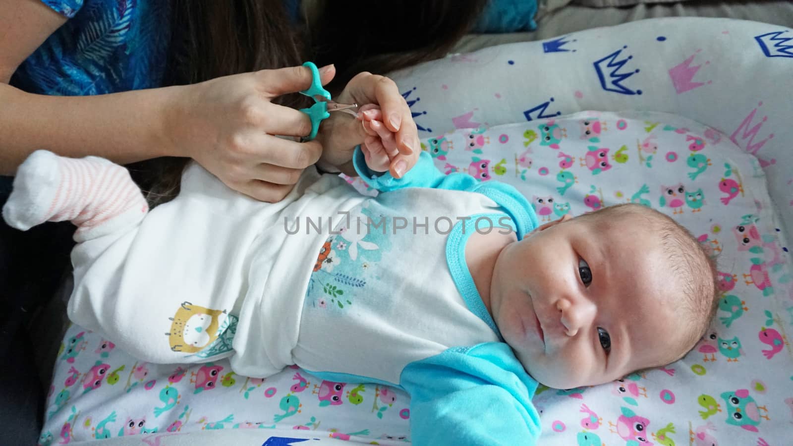 A newborn child's nails are cut with scissors. by Passcal