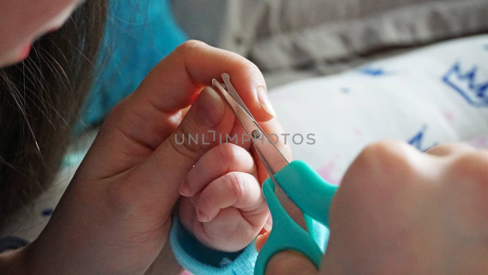 A newborn child's nails are cut with scissors. by Passcal