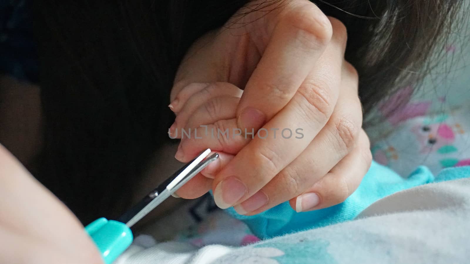 A newborn child's nails are cut with scissors. by Passcal