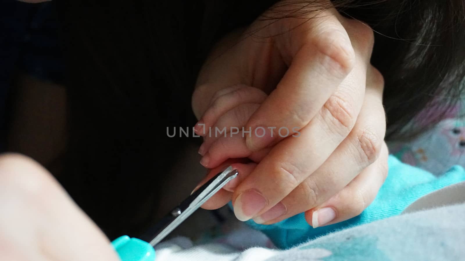 A newborn child's nails are cut with scissors. by Passcal