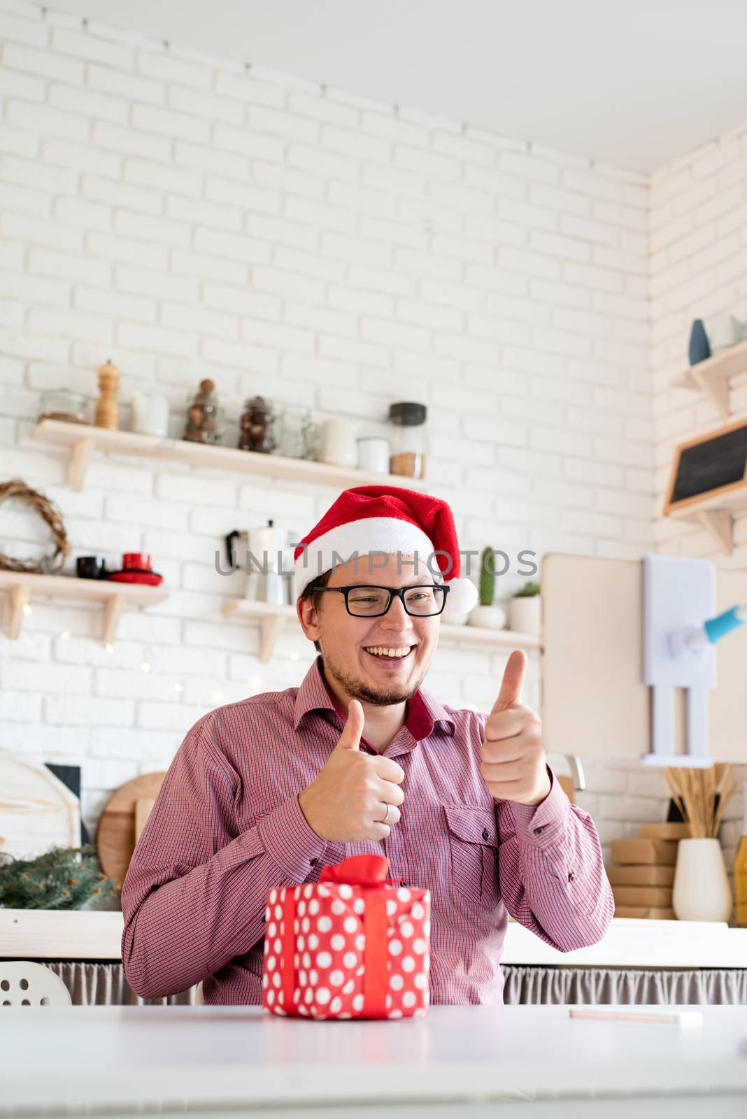 Christmas online greetings. Happy young man in santa hat greeting his friends in video chat or call on tablet clapping his hands showing thumbs up