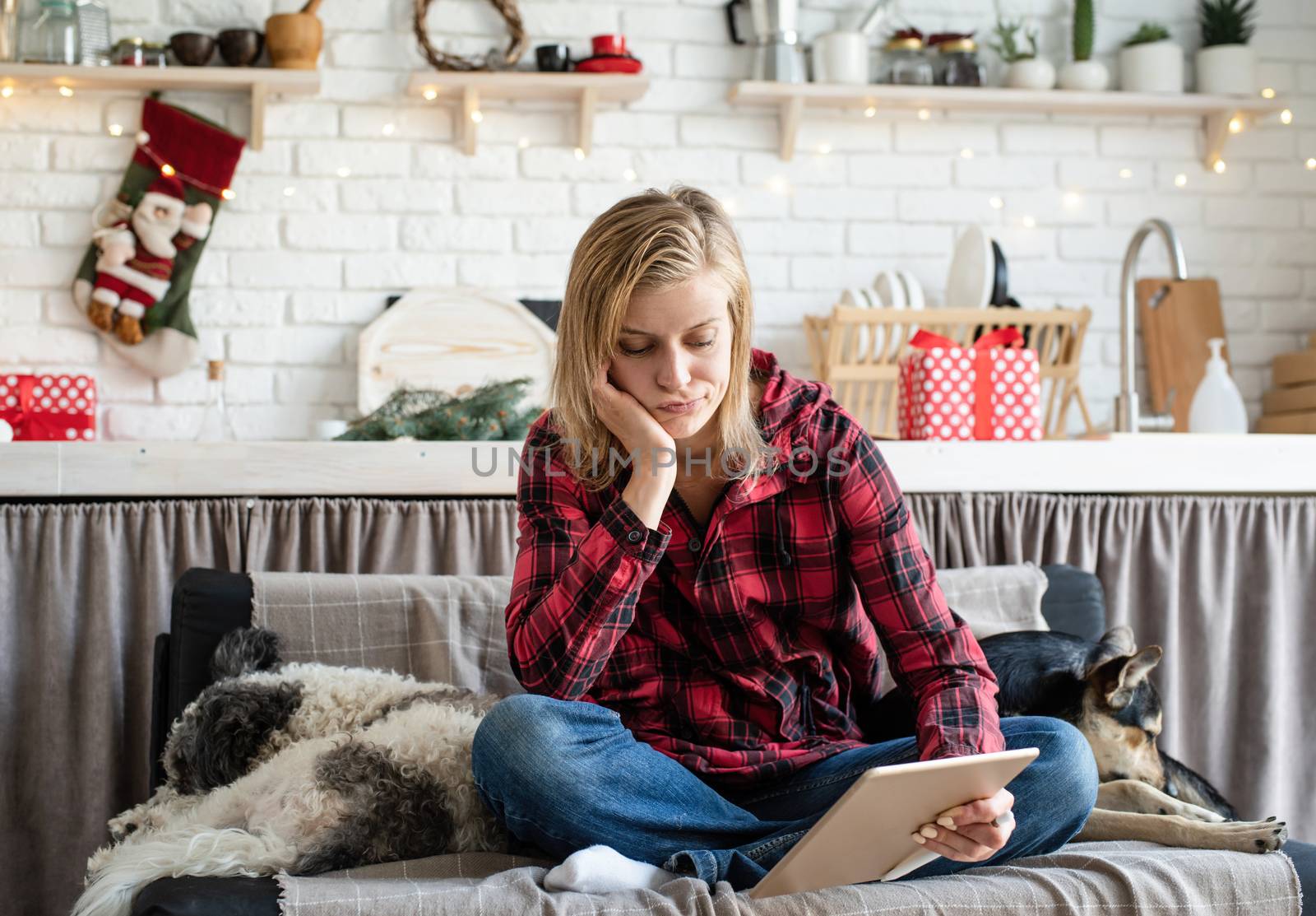 young sad woman in working on tablet sitting on the couch by Desperada