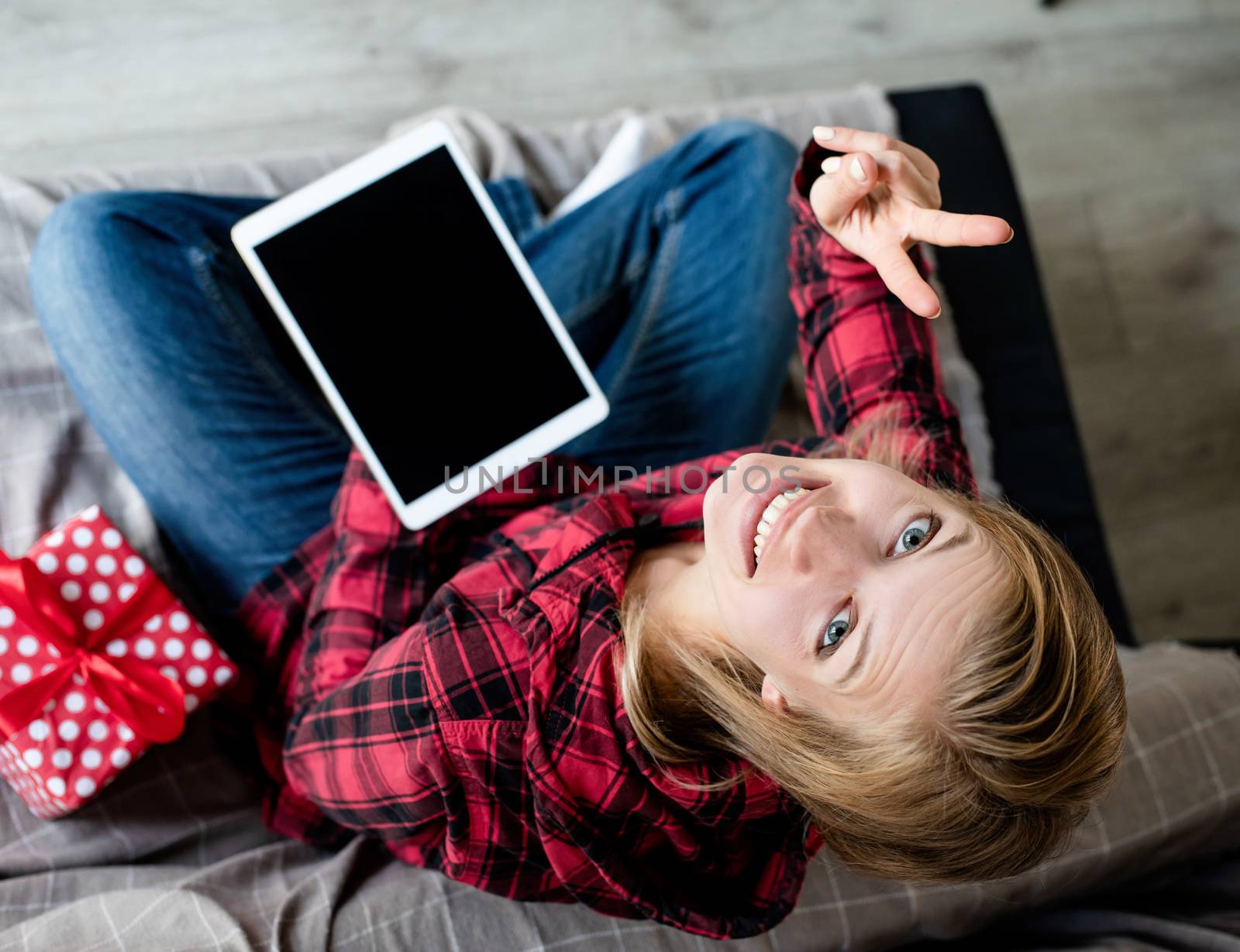 Christmas online greetings. young blond woman working on tablet sitting on the couch top view