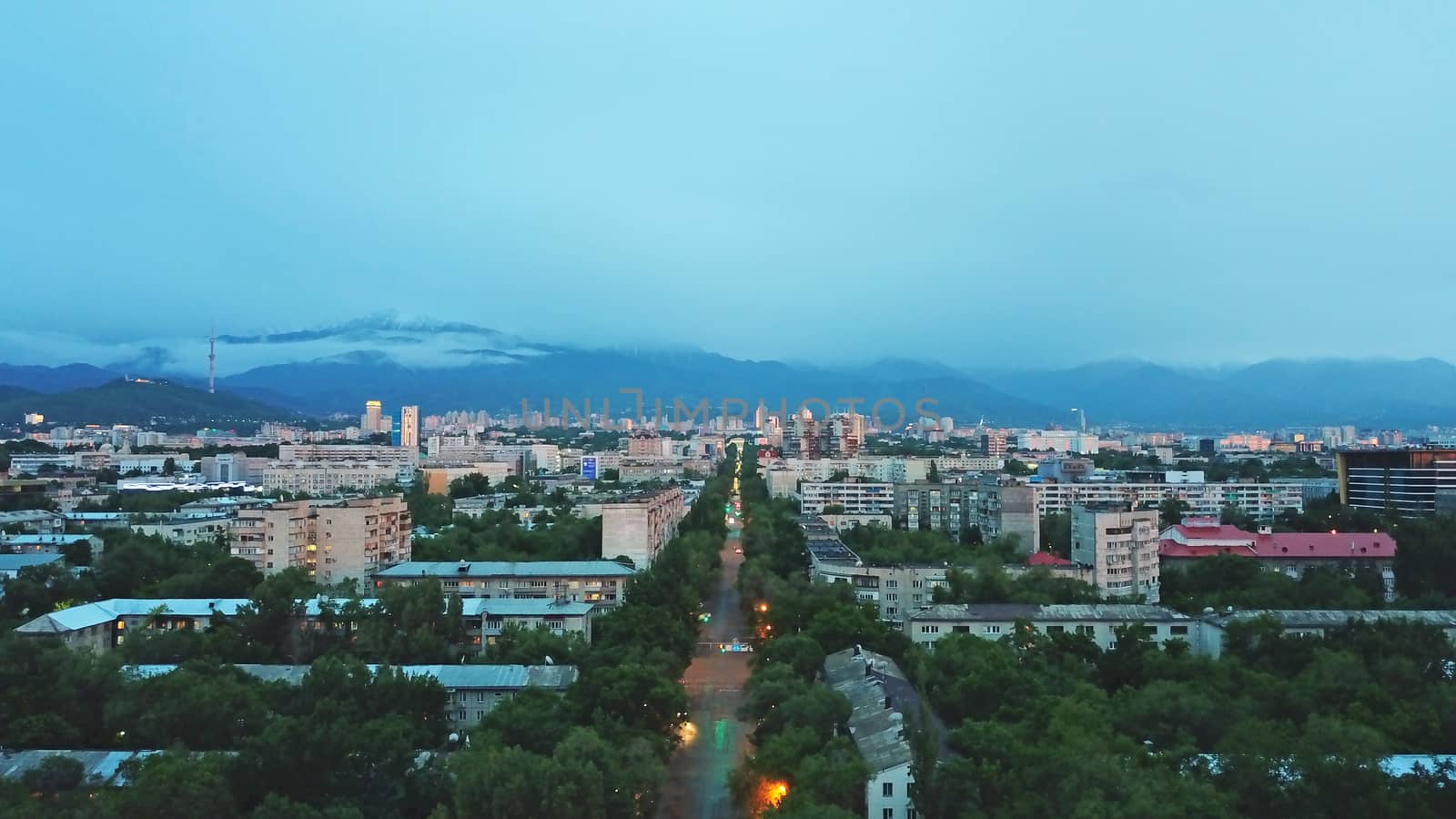 Clouds over mountains and city of Almaty at sunset by Passcal