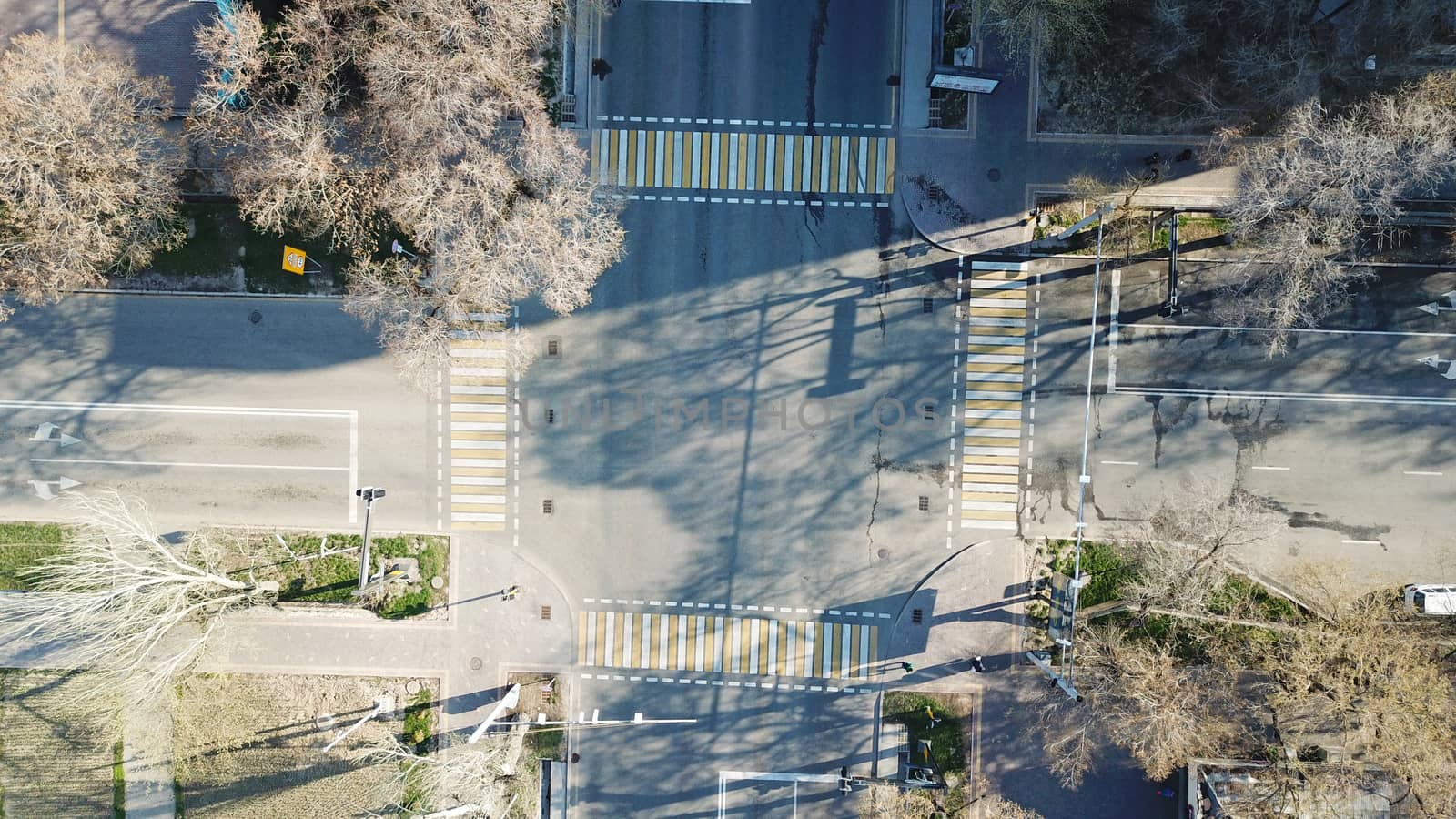 Top view of a road junction in the city of Almaty. The vehicle is waiting for the traffic light signal and is moving in its own direction. Cars, buses, and people move through the intersection.