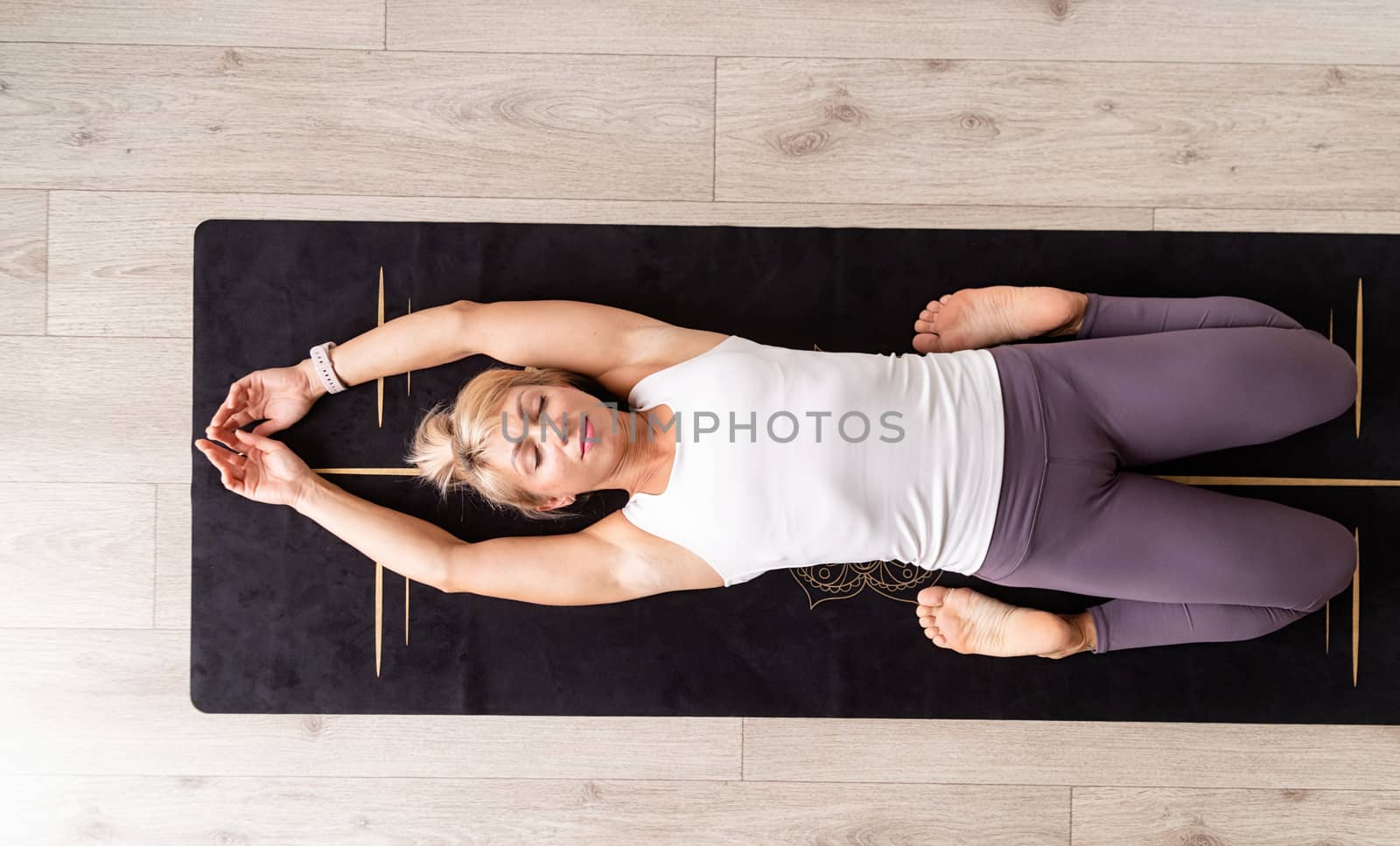 Healthy lifestyle. Young attractive woman practicing yoga, wearing sportswear, white shirt and purple pants, indoor full length, gray background