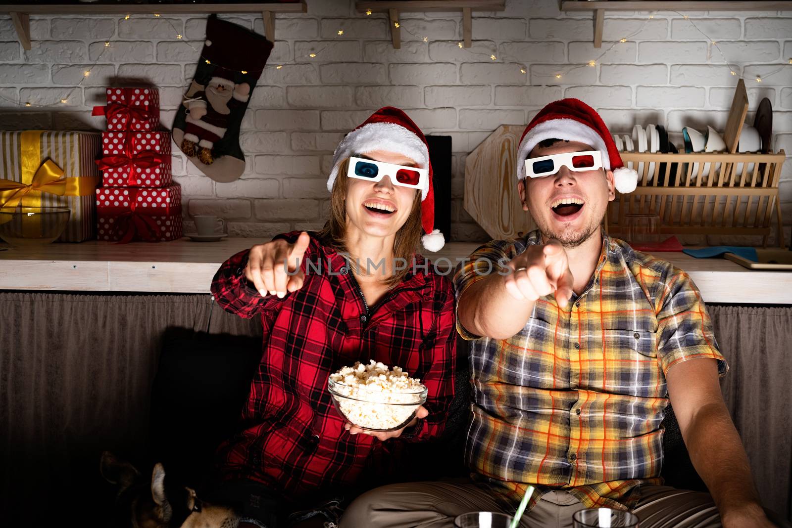 Young couple in 3D glasses watching movies at home at christmas by Desperada