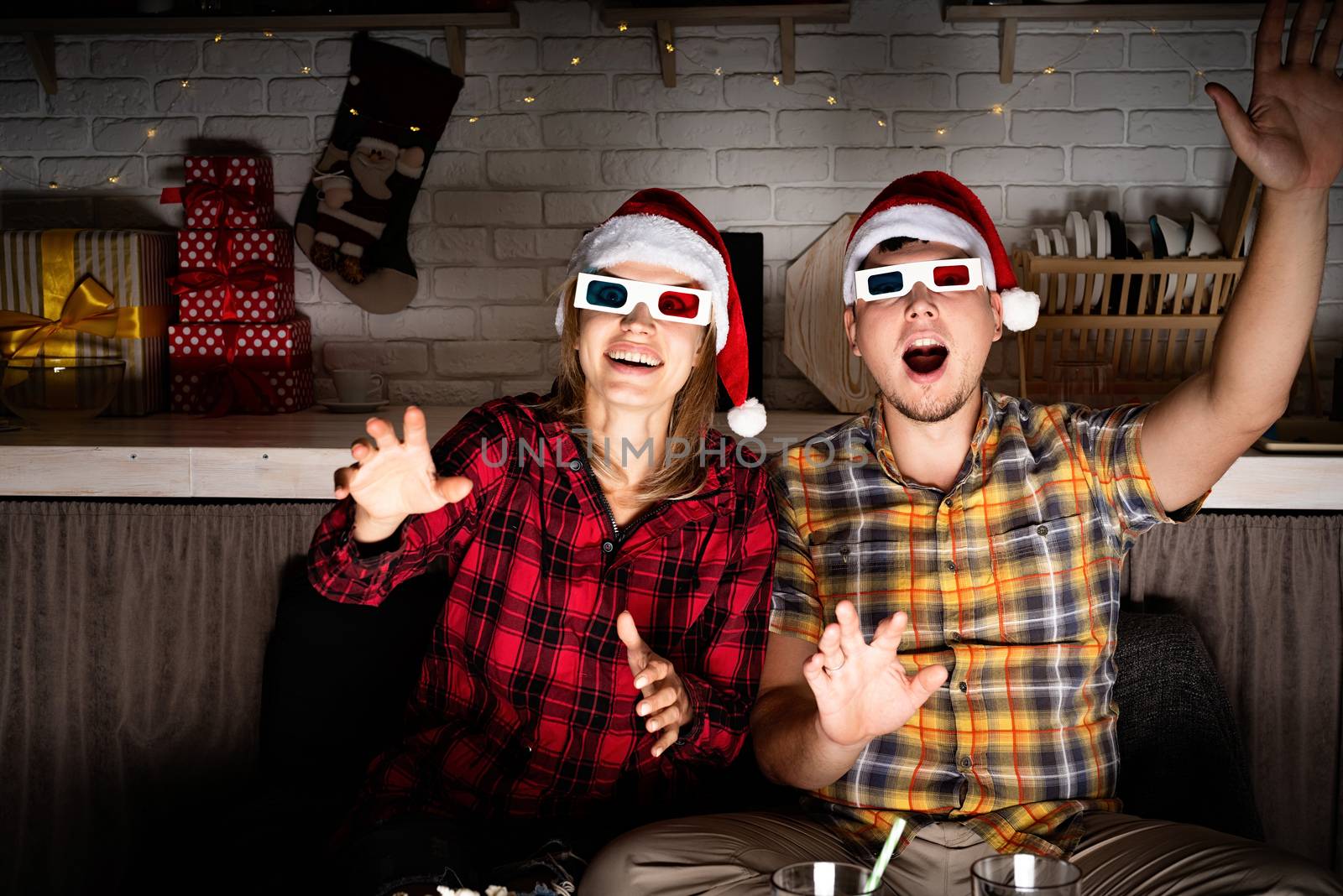 Young couple in 3D glasses watching movies at home at christmas by Desperada