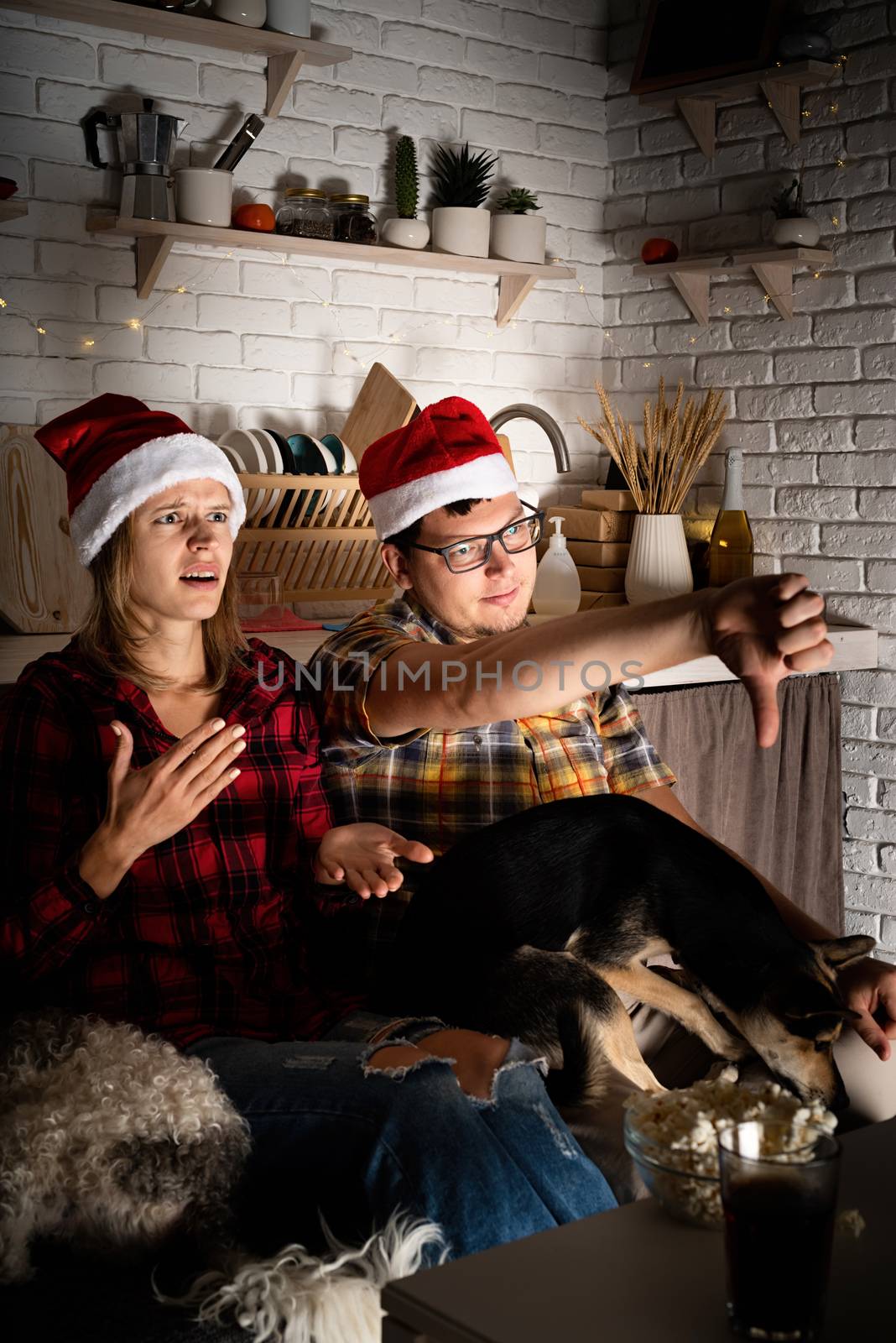 Young couple watching movies at home at christmas pointing to the screen by Desperada