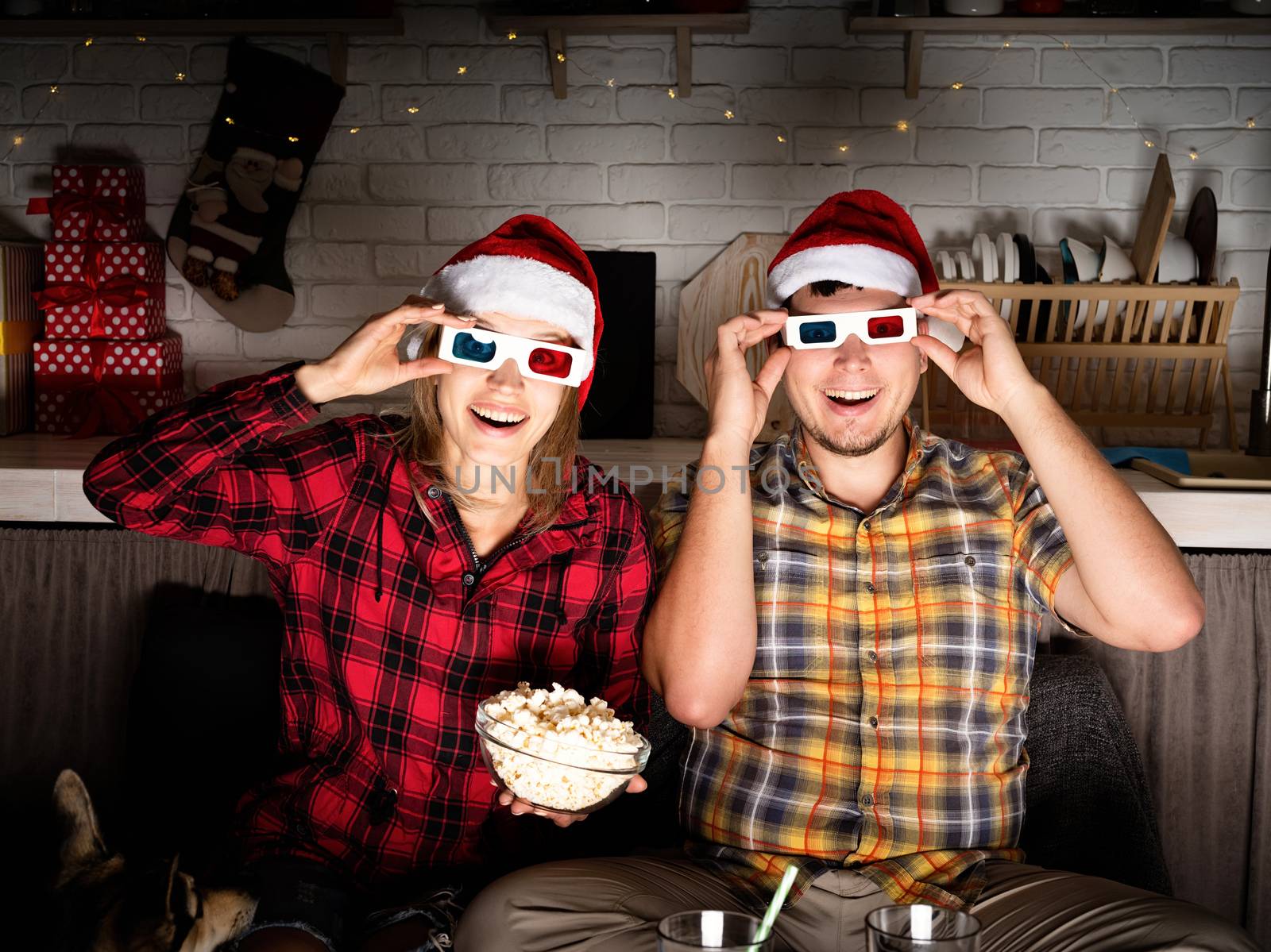 Young couple in 3D glasses watching movies at home at christmas by Desperada