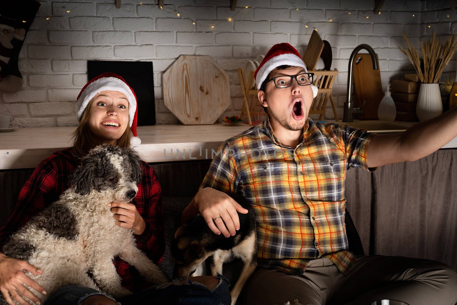Movie night. Young couple showing surprise watching movies at home at christmas