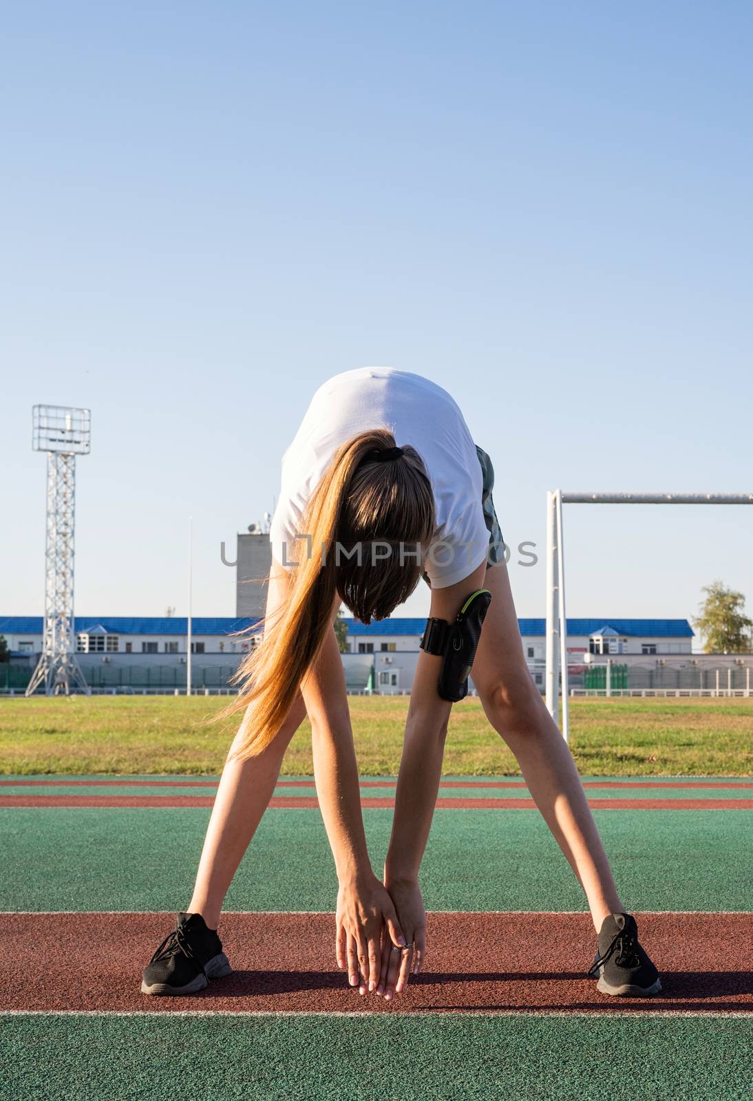 Young woman doing stretching at the stadium by Desperada