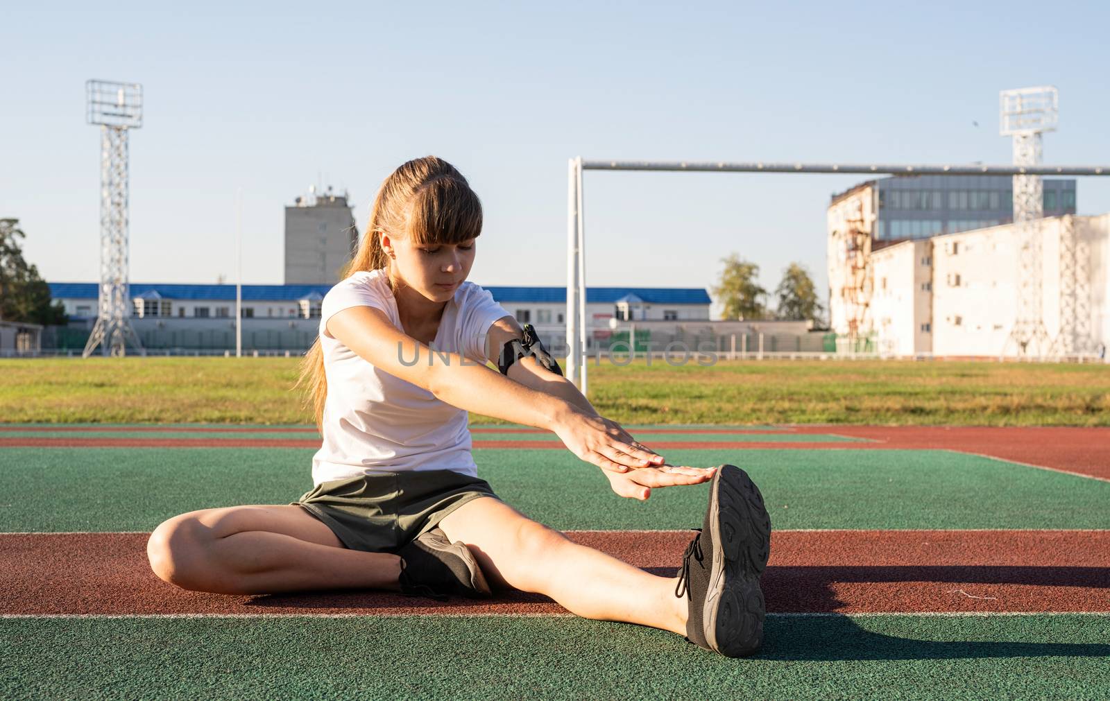 Teenager girl doing stretching at the stadium by Desperada