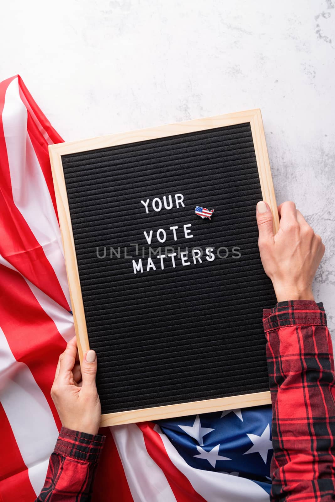 Black letter board with the text your vote matters with American flag on white marble background