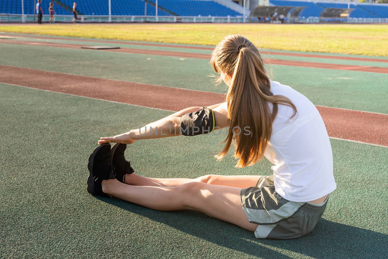 Teenager girl doing stretching at the stadium by Desperada