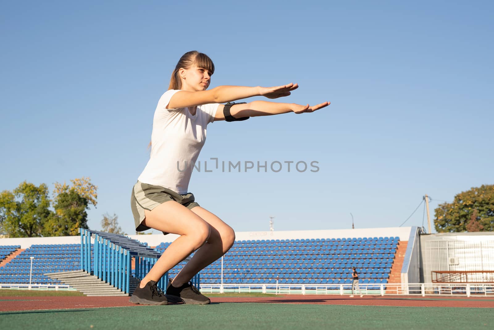 Young woman warming up at the stadium by Desperada