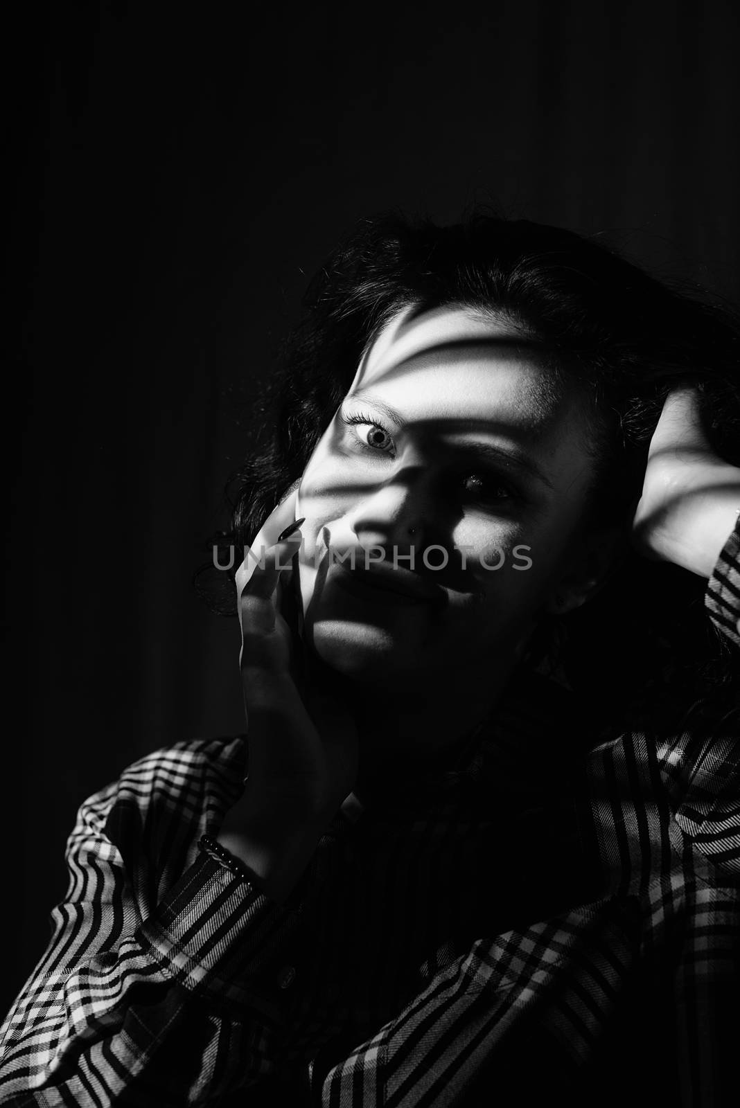 Light and shadow portrait. Black and white. Beautiful young woman with a shadow pattern on the face in the form of stripes