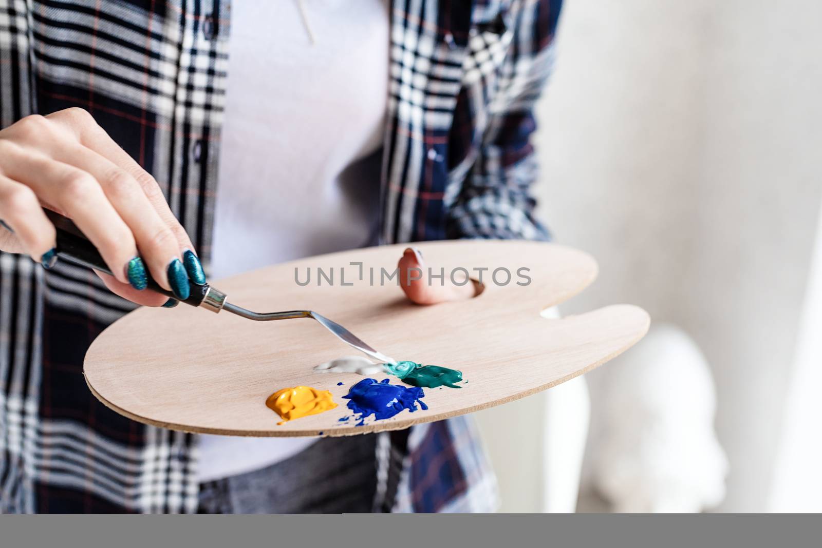 Close up of woman artist hands mixing colors on wooden art palette by Desperada