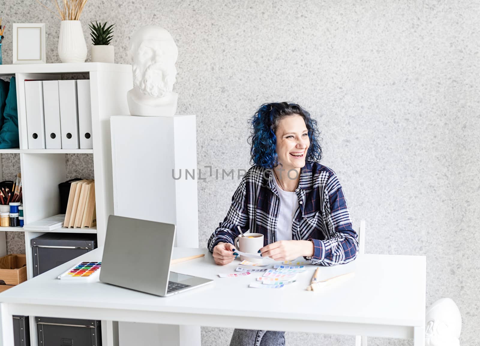 Designer working with colour palettes and laptop in her studio by Desperada