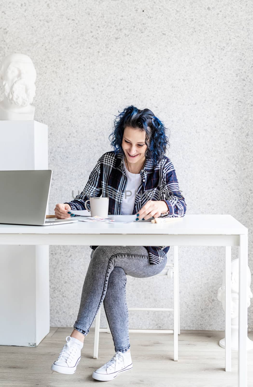 Designer working with colour palettes and laptop in her studio by Desperada