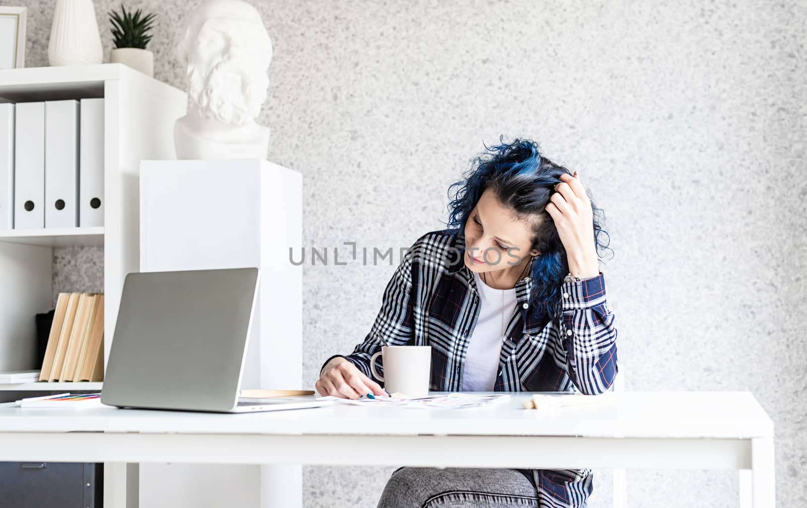 Designer working with colour palettes and laptop in her studio by Desperada