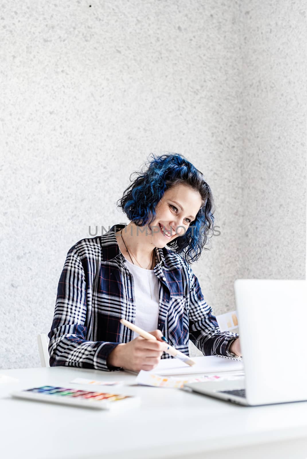 Designer working with colour palettes and laptop in her art studio