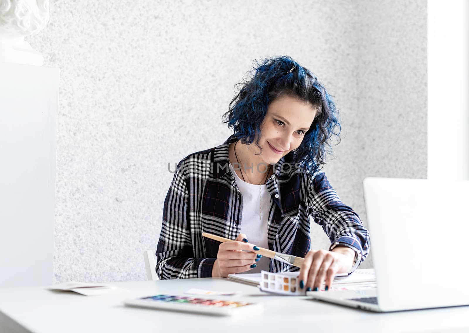 Designer working with colour palettes and laptop in her art studio